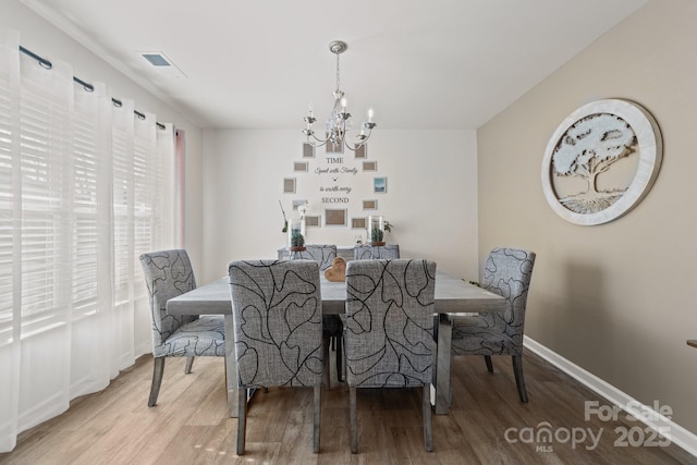 dining room with visible vents, wood finished floors, baseboards, and a chandelier