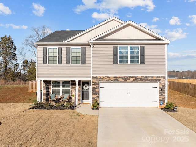 view of front facade featuring a garage, fence, stone siding, and driveway