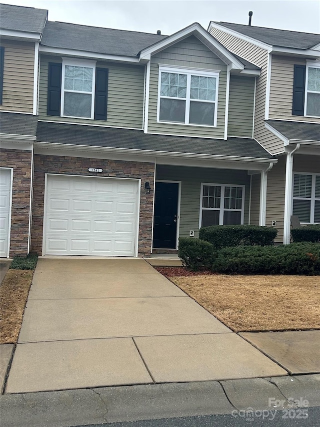multi unit property with stone siding, concrete driveway, and an attached garage