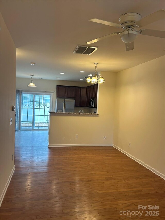 unfurnished living room with visible vents, baseboards, dark wood finished floors, recessed lighting, and ceiling fan with notable chandelier