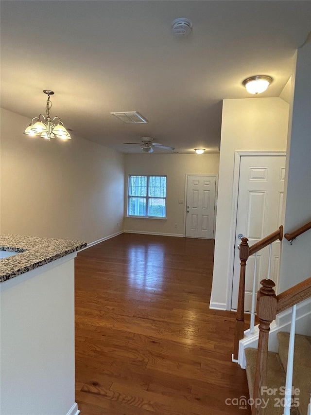 interior space with visible vents, baseboards, dark wood-style flooring, stairs, and ceiling fan with notable chandelier