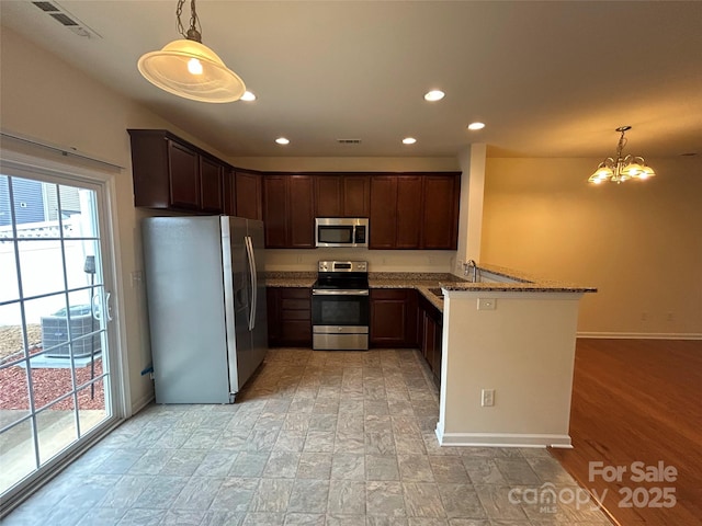 kitchen featuring visible vents, a chandelier, stone counters, a peninsula, and stainless steel appliances