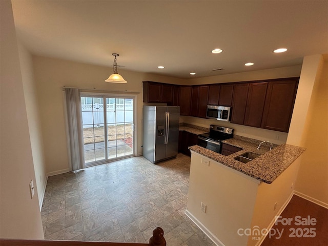 kitchen featuring baseboards, stone counters, a peninsula, a sink, and stainless steel appliances