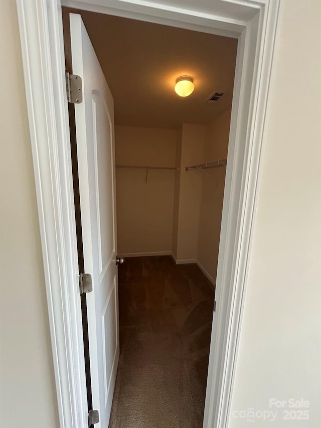 spacious closet with dark colored carpet and visible vents