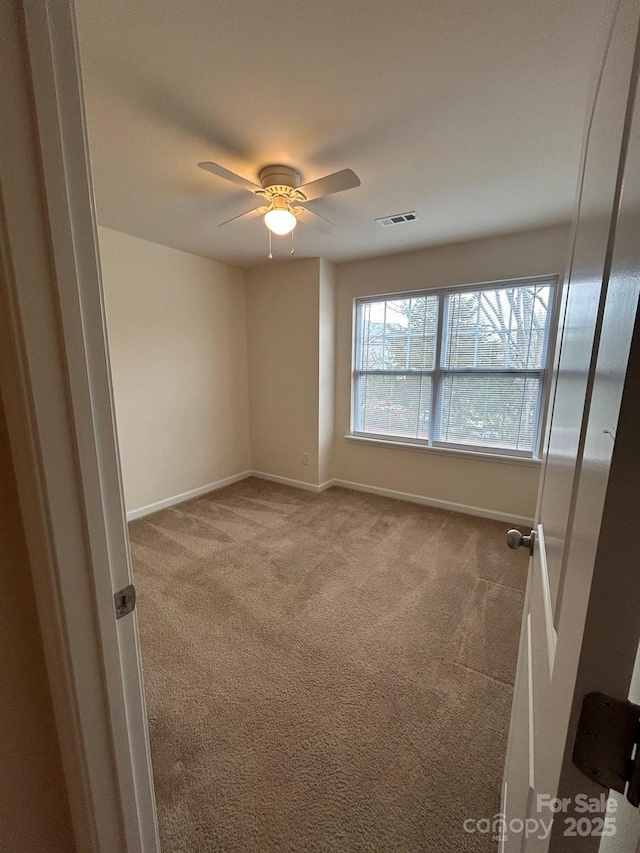 spare room featuring visible vents, carpet flooring, baseboards, and a ceiling fan