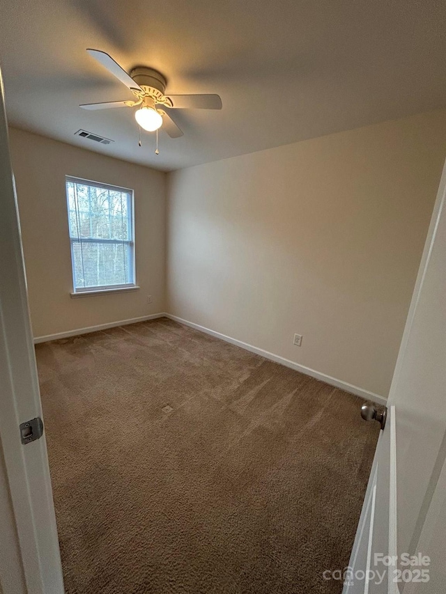 carpeted empty room featuring baseboards, visible vents, and ceiling fan