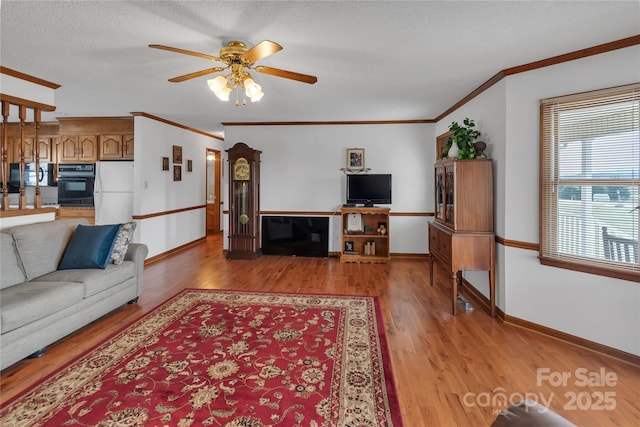 living area with light wood finished floors, baseboards, a textured ceiling, and ceiling fan