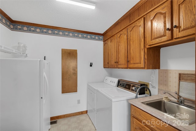 clothes washing area featuring washing machine and clothes dryer, visible vents, baseboards, cabinet space, and a sink