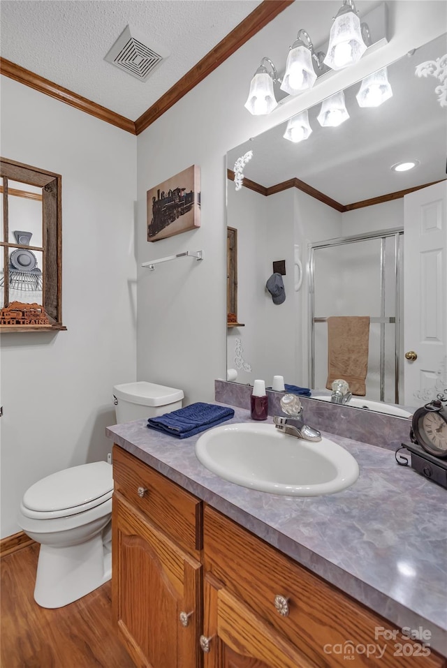 bathroom featuring visible vents, toilet, a shower stall, crown molding, and vanity