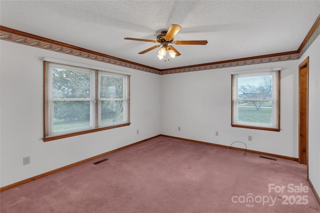 spare room with carpet flooring, visible vents, baseboards, and a textured ceiling