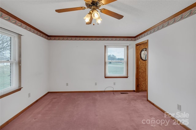 unfurnished room featuring baseboards, crown molding, carpet, and a ceiling fan