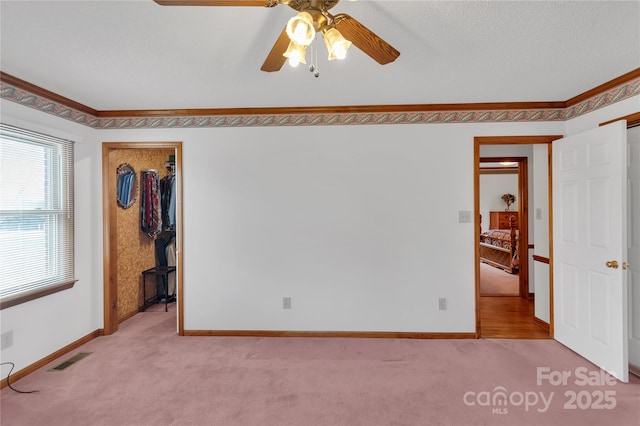 unfurnished bedroom featuring visible vents, baseboards, carpet, and crown molding