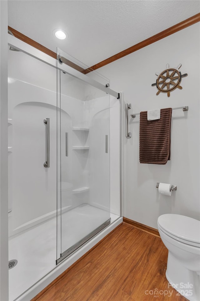 bathroom featuring a stall shower, baseboards, toilet, and wood finished floors