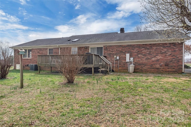 back of property with a deck, a lawn, brick siding, and a chimney