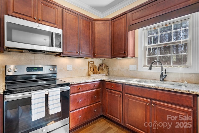 kitchen with a sink, crown molding, backsplash, and stainless steel appliances