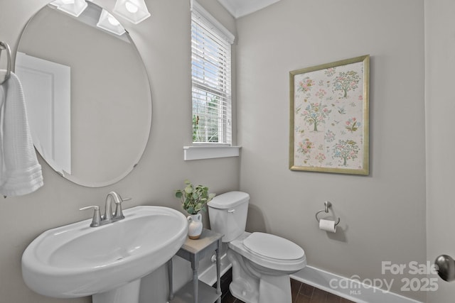 bathroom featuring wood finished floors, toilet, baseboards, and a sink