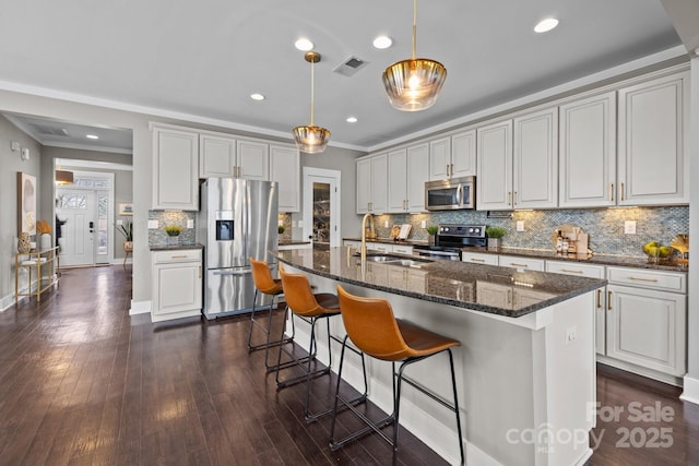 kitchen featuring visible vents, dark wood-type flooring, a sink, decorative light fixtures, and appliances with stainless steel finishes