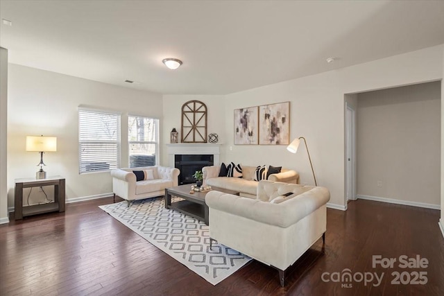 living area featuring a fireplace, visible vents, dark wood-style floors, and baseboards