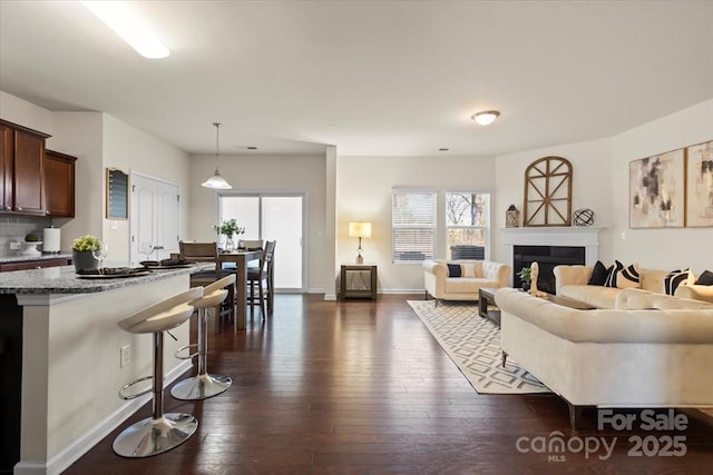 living room featuring a fireplace, dark wood-style flooring, and baseboards