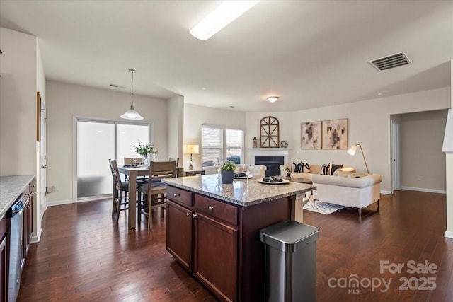 kitchen featuring visible vents, stainless steel dishwasher, dark wood finished floors, and a fireplace