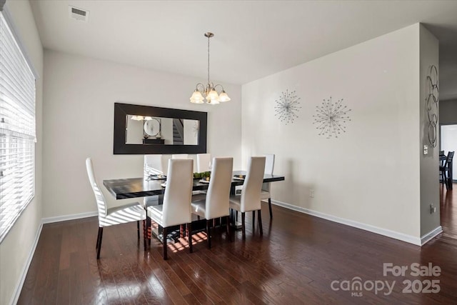 dining room featuring hardwood / wood-style flooring, a notable chandelier, baseboards, and visible vents