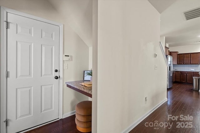 foyer with dark wood-style floors, visible vents, and baseboards