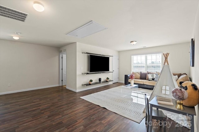 living room with visible vents, attic access, baseboards, and wood finished floors