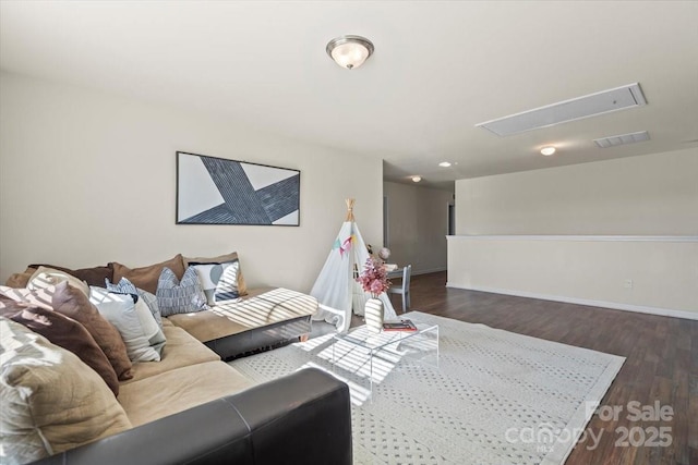 living room featuring visible vents, attic access, baseboards, and wood finished floors