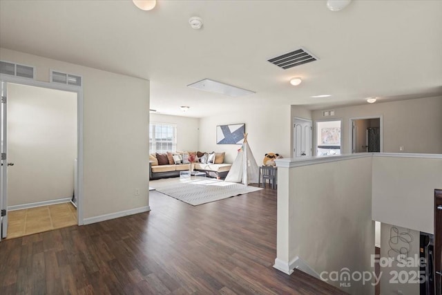 hallway featuring visible vents, baseboards, and wood finished floors