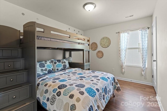 bedroom featuring visible vents, baseboards, and wood finished floors