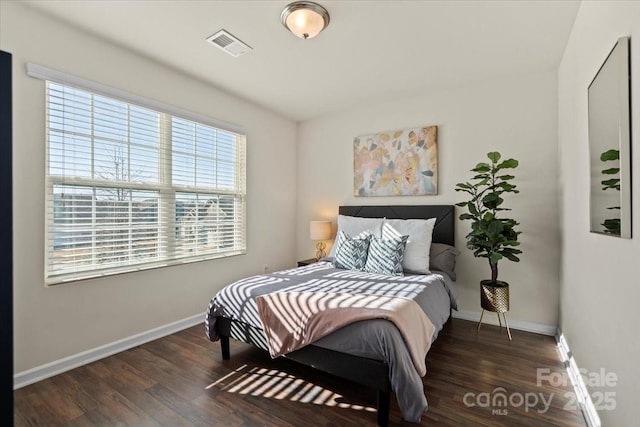 bedroom with visible vents, baseboards, and wood finished floors