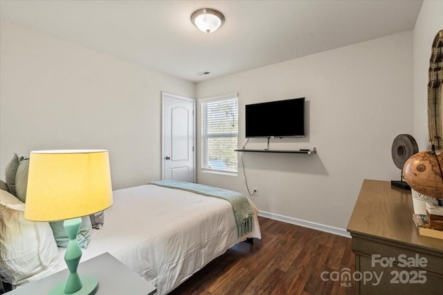 bedroom with visible vents, baseboards, and wood finished floors