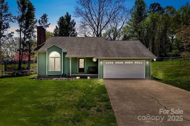 ranch-style house featuring a trampoline, concrete driveway, a front lawn, an attached garage, and fence
