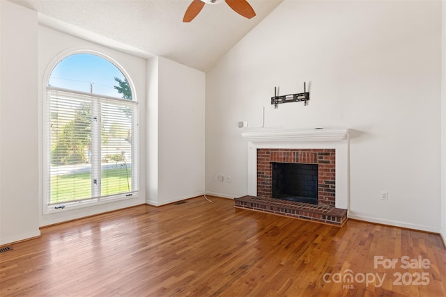 unfurnished living room with a wealth of natural light, a brick fireplace, wood finished floors, and ceiling fan