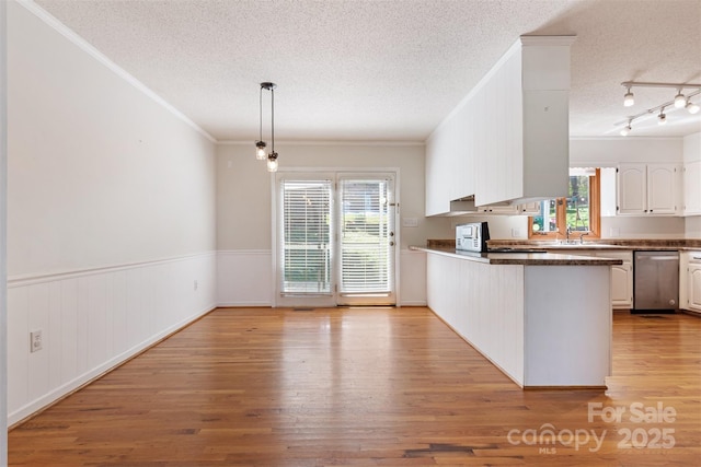 kitchen featuring a peninsula, dishwasher, a textured ceiling, and light wood finished floors