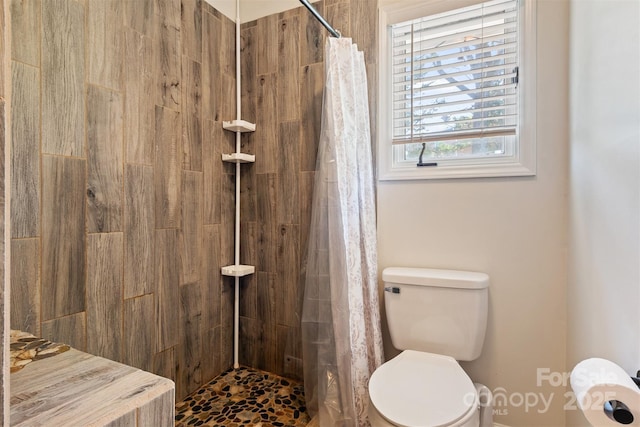 bathroom featuring toilet and a tile shower
