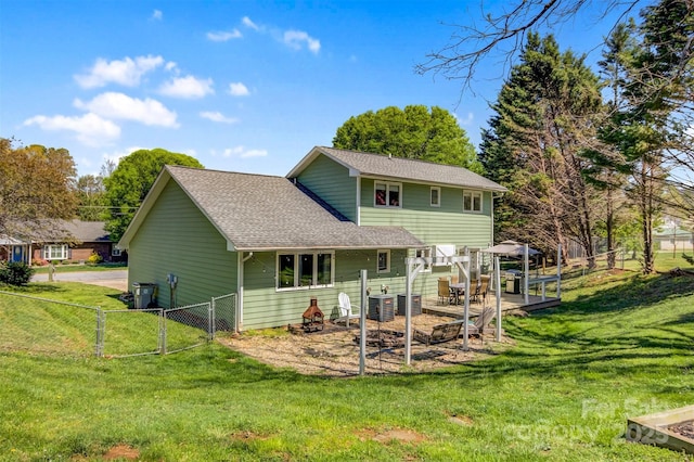 back of house with a yard, an outdoor fire pit, roof with shingles, a gate, and a gazebo