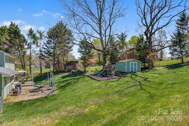 view of yard with a shed, fence, a playground, and an outbuilding