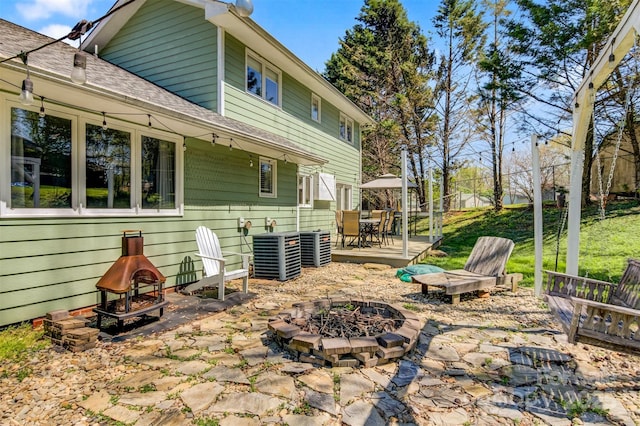 back of house featuring roof with shingles, a patio, a fire pit, and central AC unit