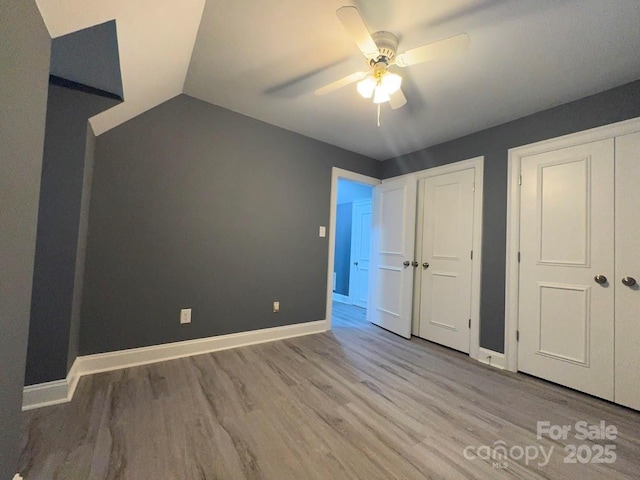 unfurnished bedroom featuring lofted ceiling, wood finished floors, baseboards, and ceiling fan