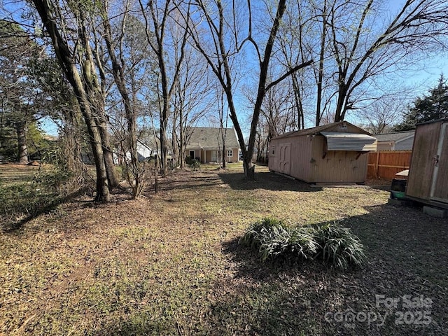 view of yard featuring an outbuilding, a storage shed, and fence