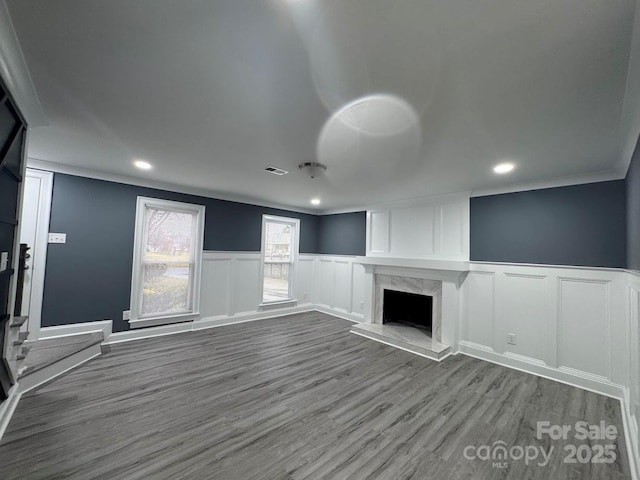 unfurnished living room featuring wood finished floors, visible vents, recessed lighting, a fireplace, and crown molding