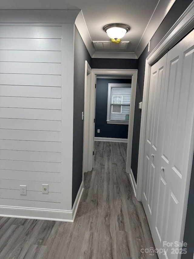 hall with crown molding, wood finished floors, and baseboards