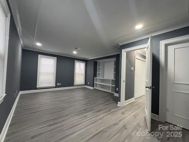 spare room featuring built in shelves, wood finished floors, baseboards, and ornamental molding