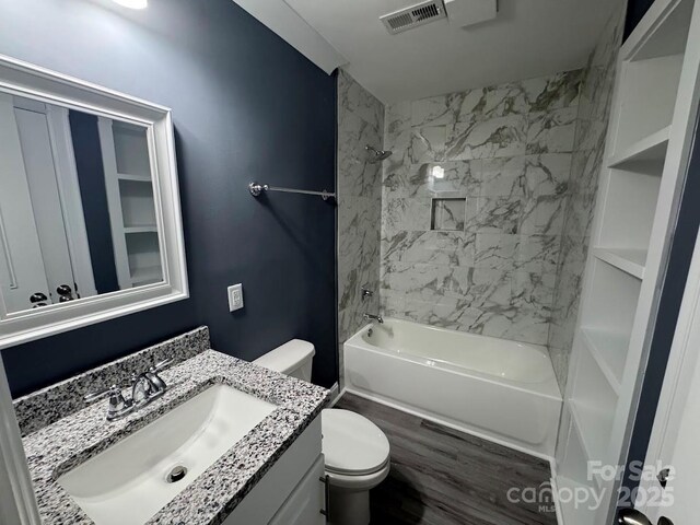 bathroom with visible vents, toilet, wood finished floors,  shower combination, and vanity