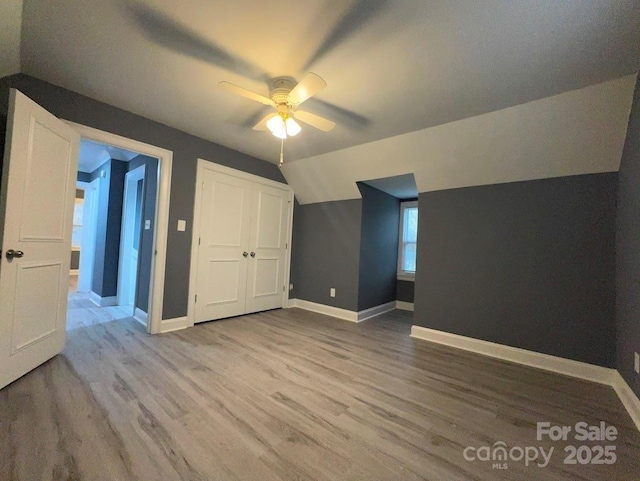 additional living space featuring a ceiling fan, vaulted ceiling, wood finished floors, and baseboards