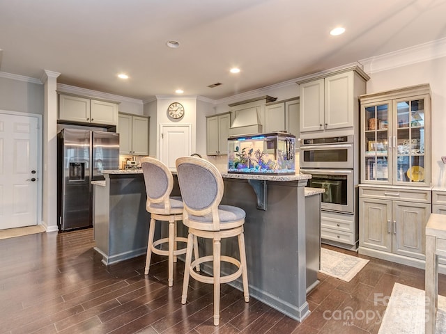 kitchen with dark wood-type flooring, a breakfast bar area, an island with sink, and appliances with stainless steel finishes