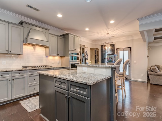 kitchen featuring visible vents, ornamental molding, gray cabinets, stainless steel appliances, and custom exhaust hood