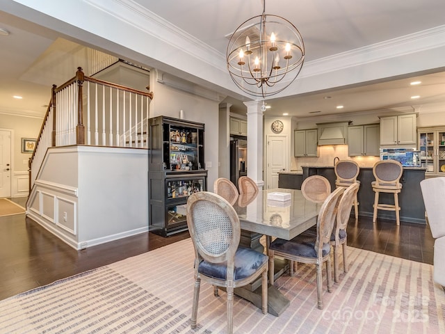 dining space featuring stairway, wood finished floors, crown molding, and ornate columns