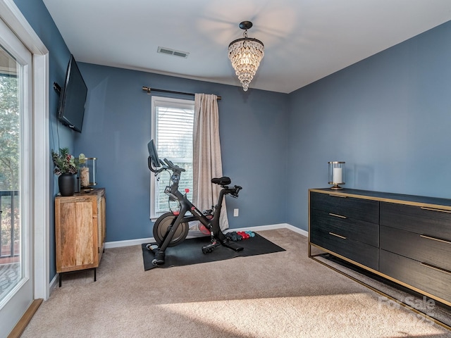 exercise area featuring visible vents, light colored carpet, baseboards, and an inviting chandelier